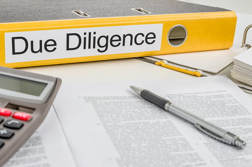 Yellow binder with Due Diligence label alongside calculator and pen